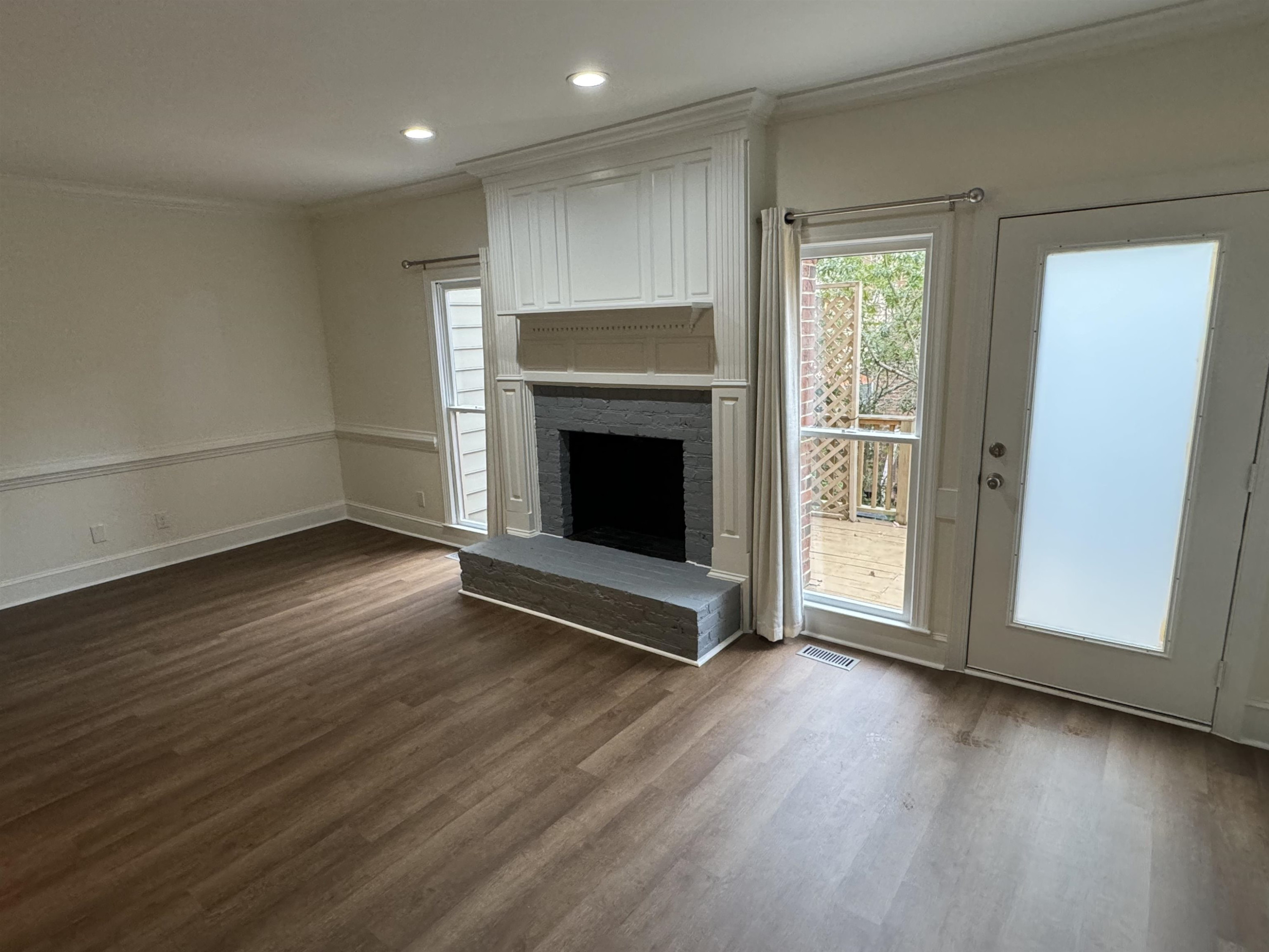 1419 Fowlkes Place Raleigh, NC 27612 - Photo 4 of 9 an empty room with wooden floor fireplace and windows