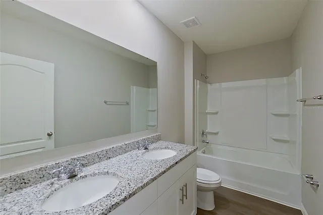 a bathroom with a granite countertop sink a toilet and shower
