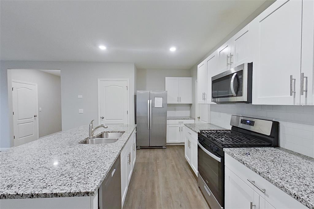 32037 Katelin Circle Leesburg, FL 34748 - Photo 5 of 20 a kitchen with stainless steel appliances granite countertop a sink stove and refrigerator