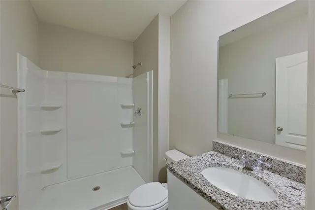 a bathroom with a granite countertop sink toilet and shower