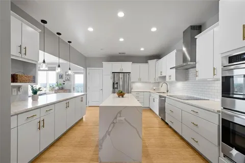 a large kitchen with stainless steel appliances lots of counter space and wooden floor