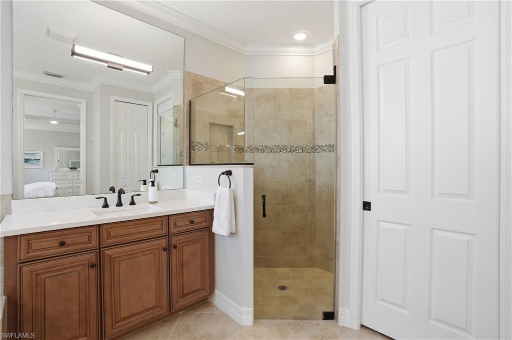 3058 Aviamar Circle Naples, FL 34114 - Photo 13 of 50 Bathroom featuring a wood-finish vanity with a white countertop, an undermount sink, and a large wall mirror