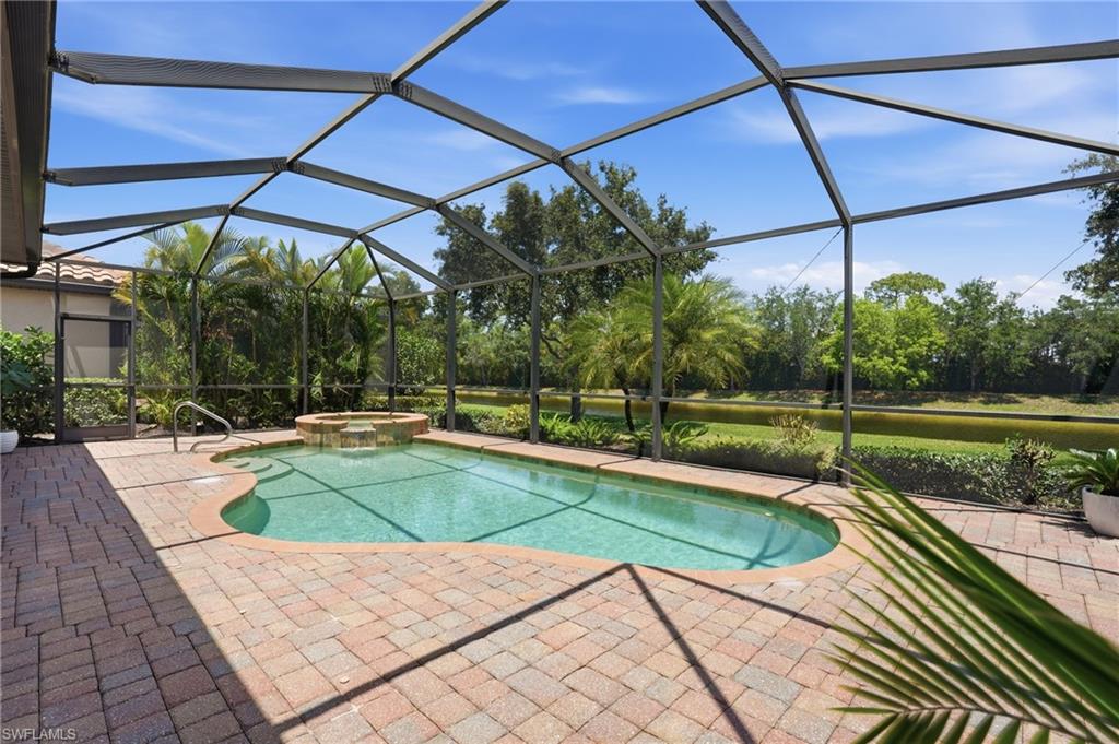 3058 Aviamar Circle Naples, FL 34114 - Photo 24 of 50 Screened outdoor living area featuring a freeform swimming pool, integrated spa with waterfall, paver deck, and tropical landscaping