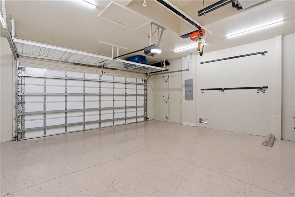 3058 Aviamar Circle Naples, FL 34114 - Photo 29 of 50 Expansive garage featuring an overhead garage door, a finished floor, overhead storage racks, and built-in wall storage hooks