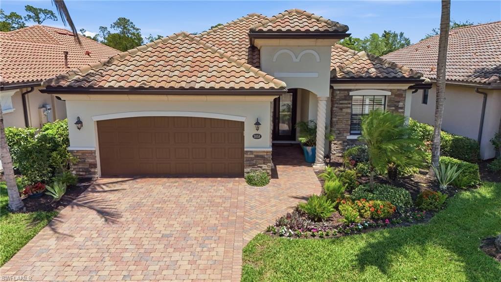 3058 Aviamar Circle Naples, FL 34114 - Photo 30 of 50 Mediterranean-inspired exterior featuring a barrel tile roof, stacked stone accents, a paver driveway, and an arched entry with a decorative column