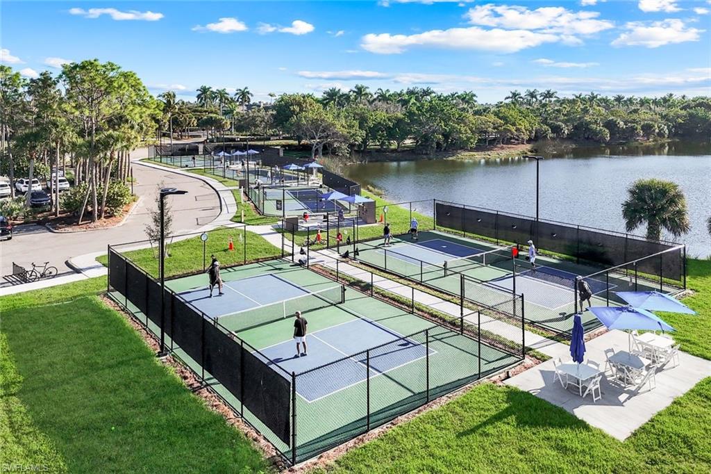 3058 Aviamar Circle Naples, FL 34114 - Photo 44 of 50 Multiple pickleball courts with perimeter fencing, surrounded by a manicured lawn and mature landscaping