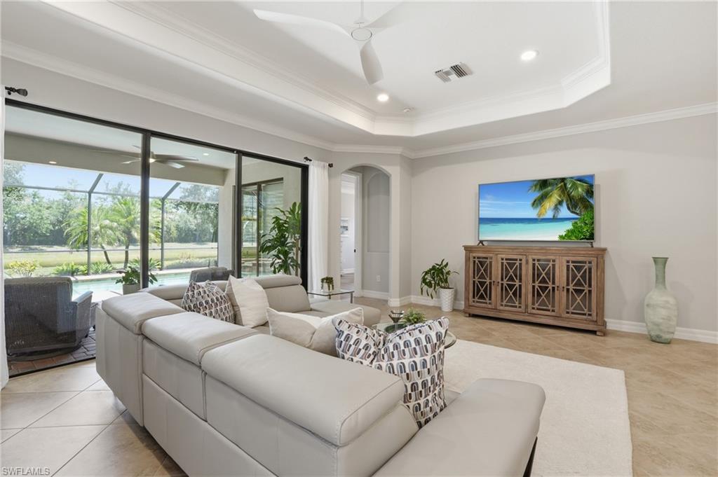 3058 Aviamar Circle Naples, FL 34114 - Photo 9 of 50 Spacious living area featuring large sliding glass doors opening to a screened lanai with a swimming pool