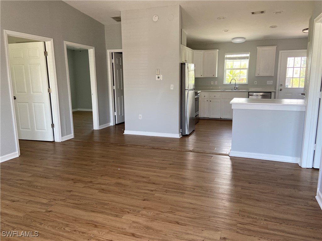 5527 Judith Road Bokeelia, FL 33922 - Photo 13 of 13 an empty room with wooden floor and a kitchen
