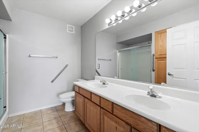a bathroom with a double vanity sink a toilet and a mirror