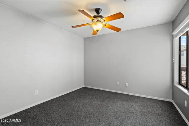 an empty room with windows and fan