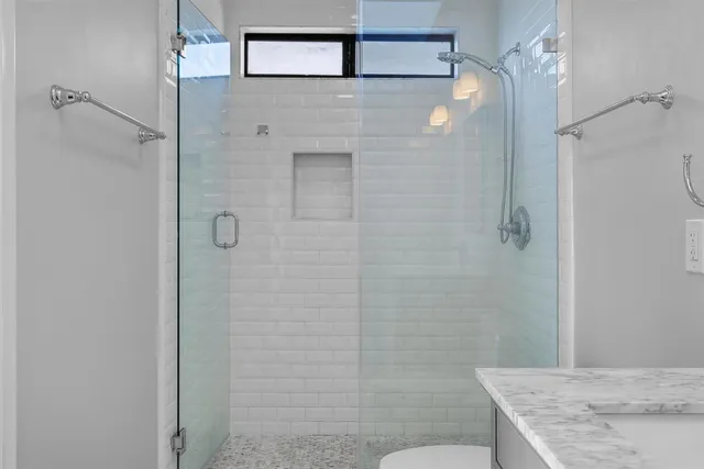 a view of a hallway with wooden floor and a bathroom