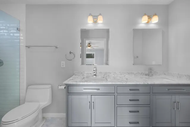 a bathroom with a granite countertop sink a toilet and shower