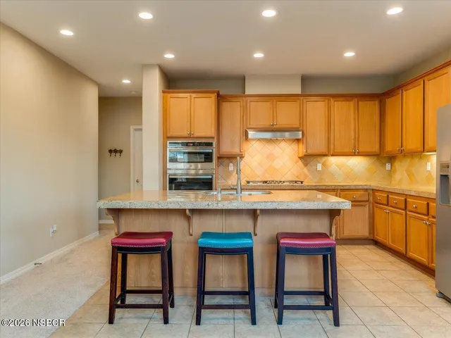 a kitchen with stainless steel appliances granite countertop a table chairs sink and cabinets