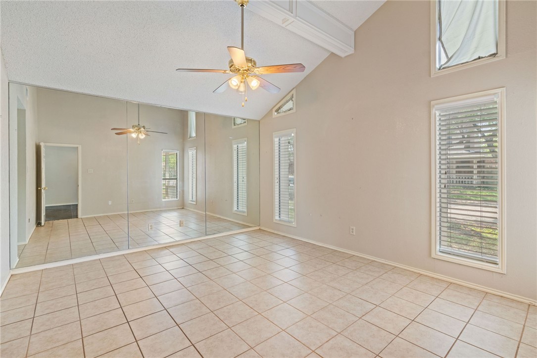 7209 Candy Ridge Road Corpus Christi, TX 78413 - Photo 18 of 24 an empty room with kitchen view and a chandelier fan