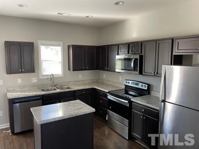 a kitchen with a sink a microwave a refrigerator and cabinets