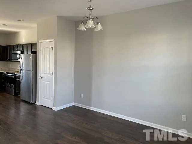 a view of a kitchen with a refrigerator a stove top oven and wooden floor