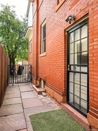 a view of backyard with brick wall and a large tree