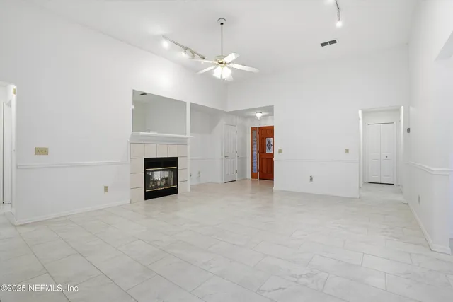 an empty room with chandelier fan and windows