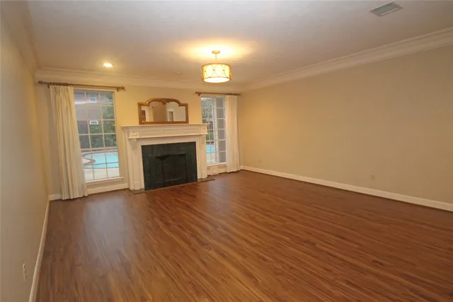 an empty room with wooden floor fireplace and windows