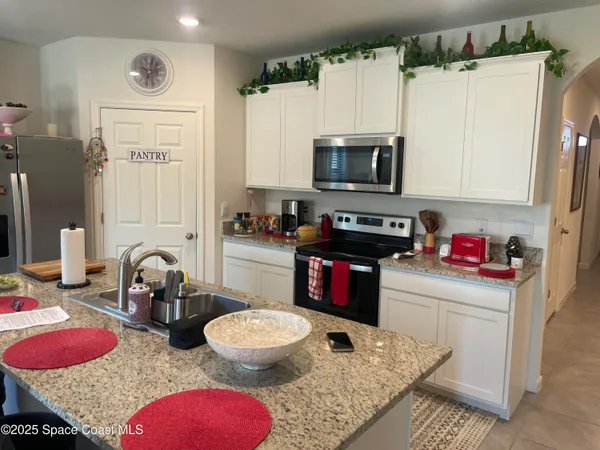 a kitchen with stainless steel appliances granite countertop a sink dishwasher a microwave oven and a dining table with chairs