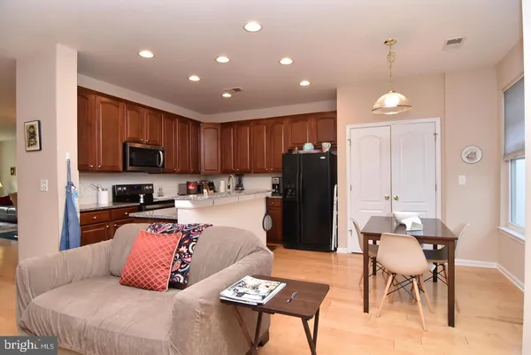 a kitchen with stainless steel appliances granite countertop a stove top oven a sink dishwasher a dining table and chairs with wooden floor