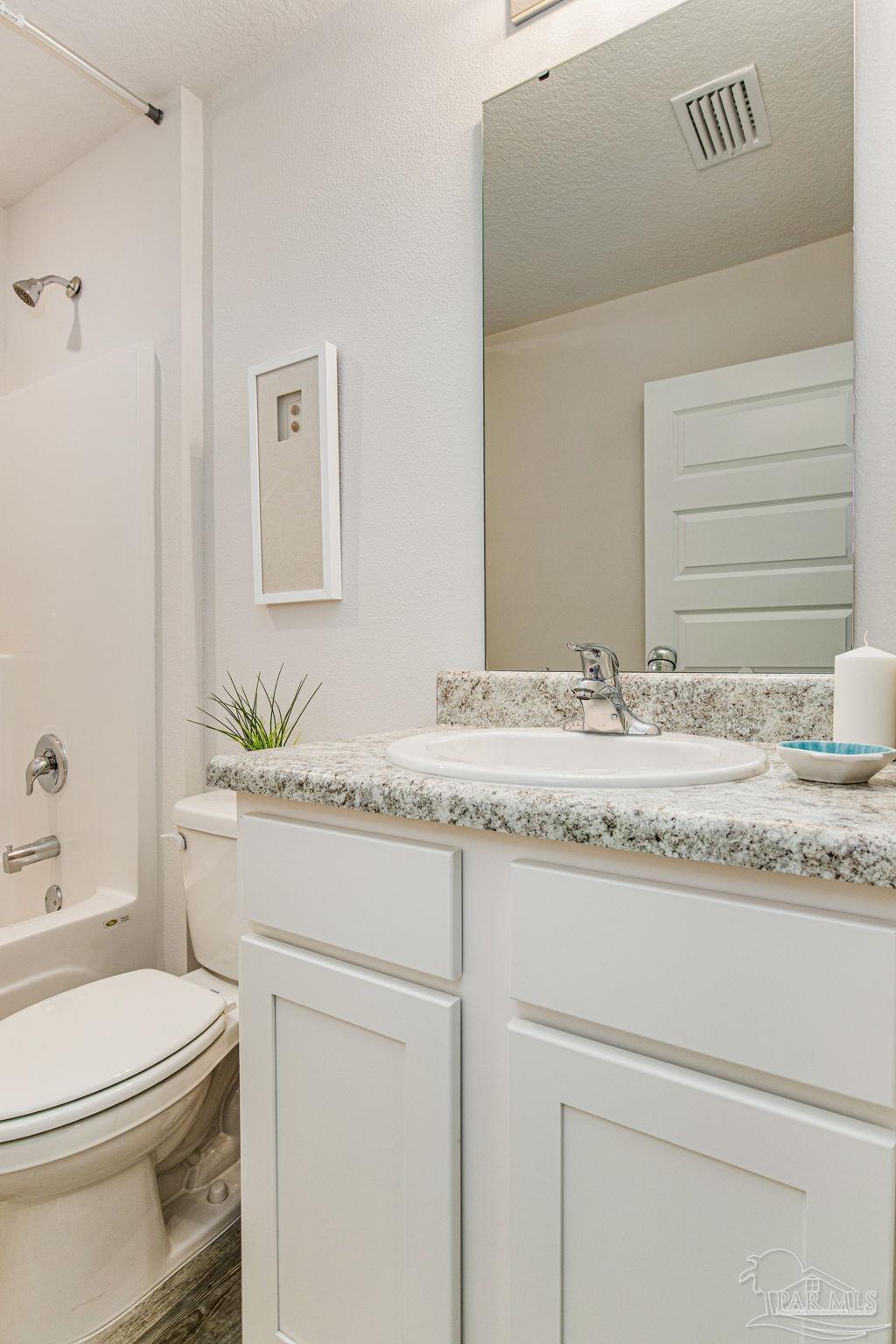 6461 Firefly Drive Milton, FL 32583 - Photo 22 of 36 a bathroom with a granite countertop sink vanity mirror and toilet