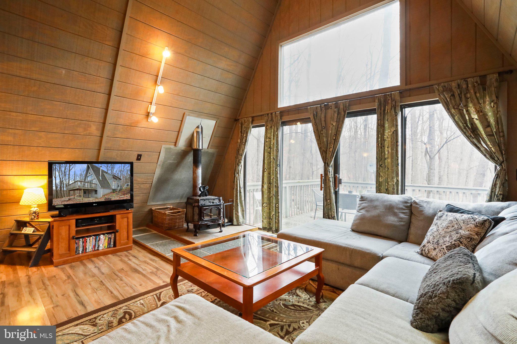 13 Mountainside Loop Berkeley Springs, WV 25411 - Photo 12 of 57 a living room with furniture a large window with projector and a flat screen tv