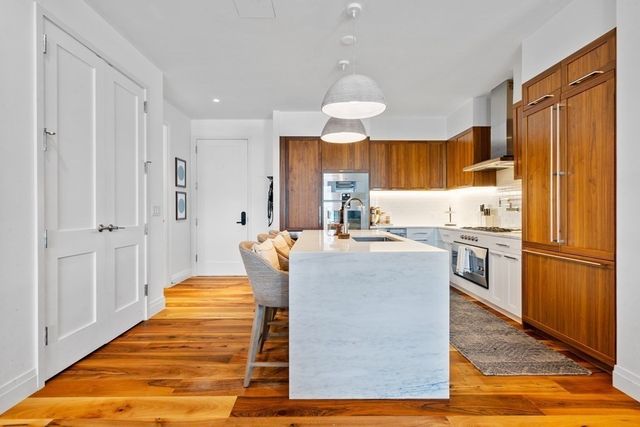 a kitchen with stainless steel appliances granite countertop a refrigerator a sink dishwasher and white cabinets with wooden floor