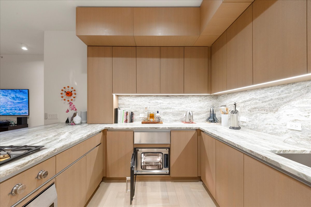 313 West 17th Street, Unit 1104 Austin, TX 78701 - Photo 14 of 40 A Gaggenau® built-in steam oven seamlessly integrated into custom Rhode Partners cabinetry, paired with 3cm Fantasy Brown marble counters and backsplash. This chef-caliber feature supports precise, healthy cooking and reinforces the kitchen’s Omakase-inspired, penthouse-level design.