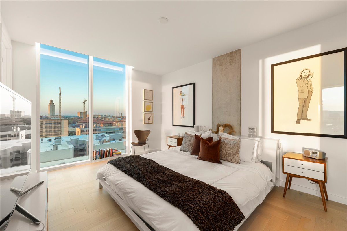 313 West 17th Street, Unit 1104 Austin, TX 78701 - Photo 6 of 40 Step into this sleek and contemporary primary bedroom with floor-to-ceiling windows that frame sweeping views of the city skyline and the UT Tower.