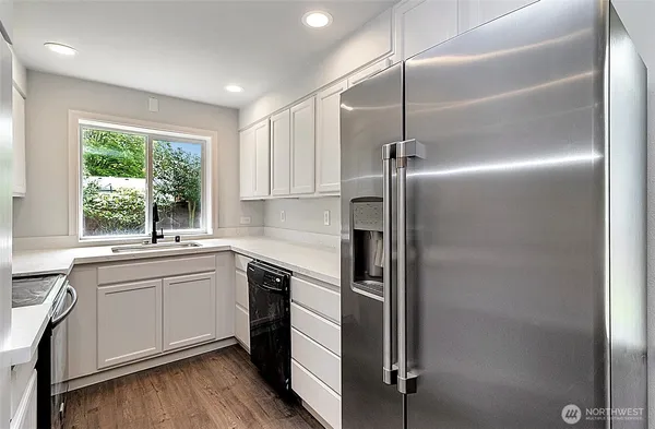 a kitchen with kitchen island white cabinets and stainless steel appliances