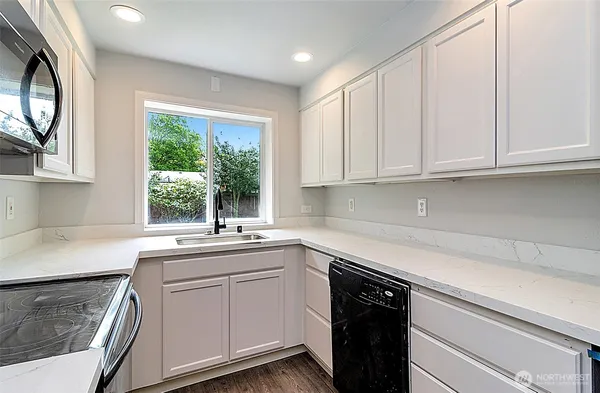 a kitchen with white cabinets and a window