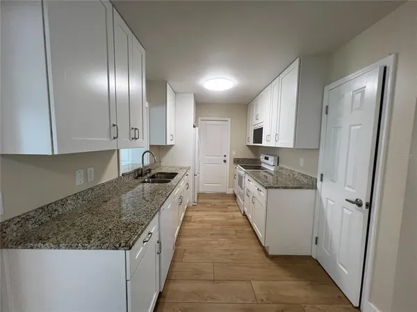 a large kitchen with stainless steel appliances granite countertop a stove a sink and a refrigerator