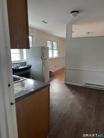 a kitchen with stainless steel appliances granite countertop a refrigerator a stove and a sink with wooden floor