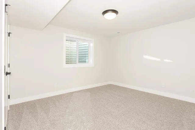an empty room with white cabinet and mirror