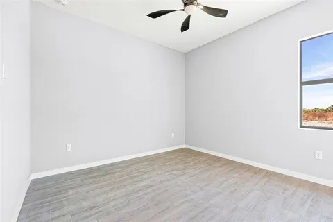 an empty room with a window and a fan