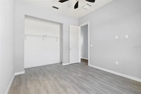 an empty room with wooden floor and ceiling fan