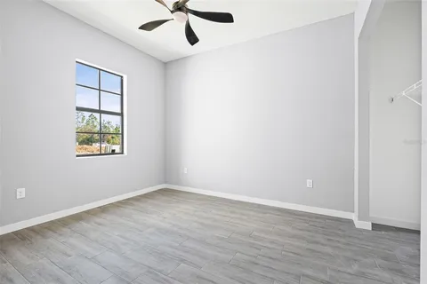 an empty room with wooden floor ceiling fan and windows