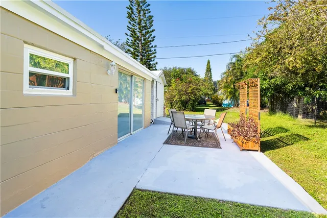 a view of a patio with table and chairs potted plants and large tree