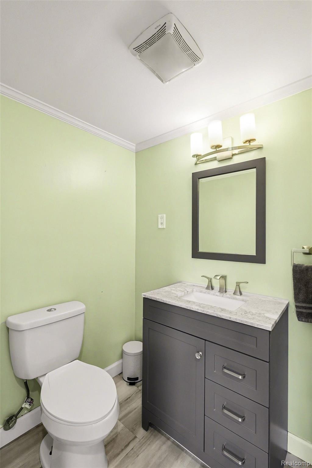 16485 Jennings Road Fenton, MI 48430 - Photo 19 of 27 Half bath with vanity, crown molding, and light wood-style flooring