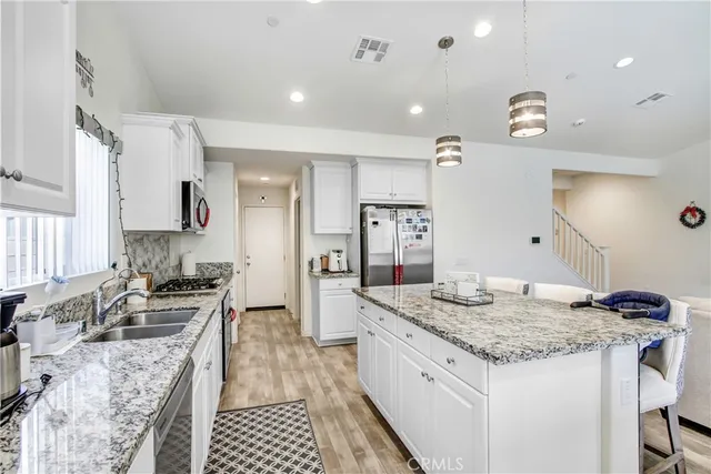 a kitchen with granite countertop kitchen island stainless steel appliances a sink stove and cabinets