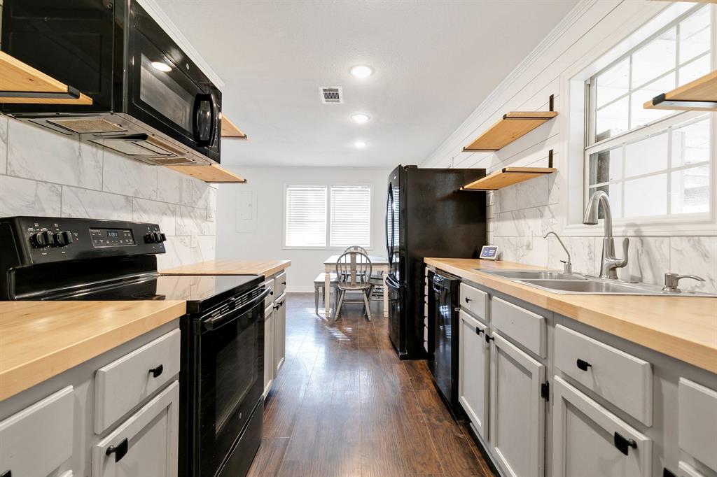 1325 Pilot Grove Road Whitewright, TX 75491 - Photo 12 of 30 Kitchen with black appliances, ornamental molding, butcher block counters, backsplash, and dark wood flooring.