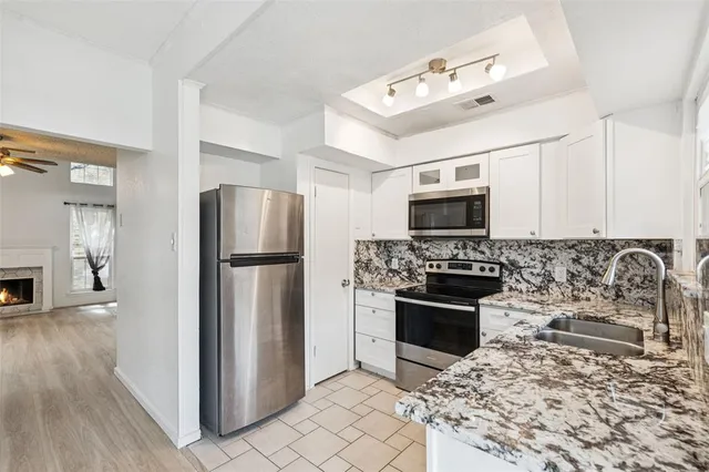 a kitchen with granite countertop a refrigerator and a stove top oven