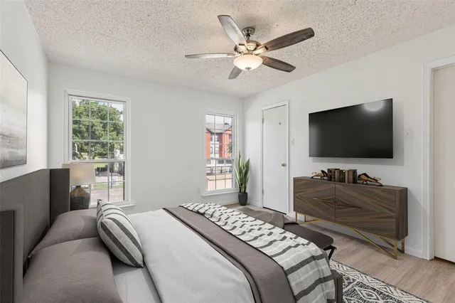 an empty room with wooden floor fan and windows