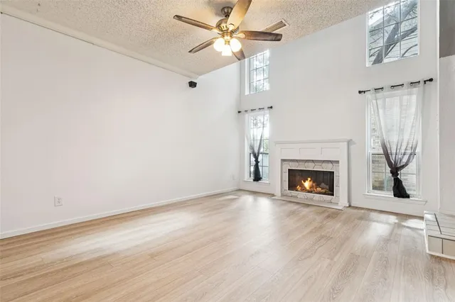 a view of an empty room with wooden floor fireplace and a window