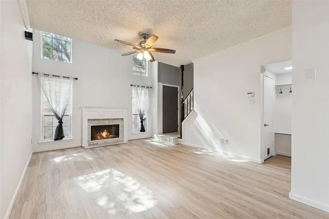 a view of empty room with wooden floor fireplace and fan