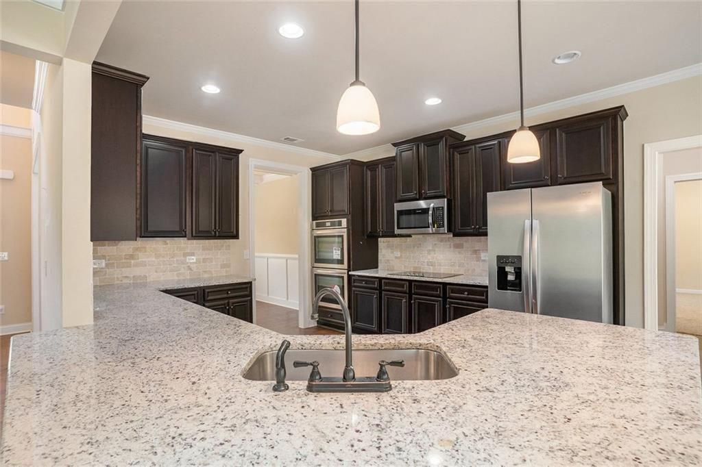381 Homestead Circle Forsyth, GA 31029 - Photo 8 of 49 a kitchen with stainless steel appliances kitchen island granite countertop a refrigerator and a sink