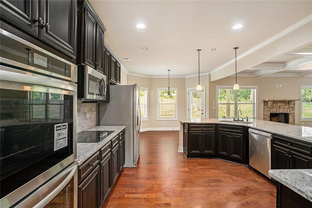 381 Homestead Circle Forsyth, GA 31029 - Photo 9 of 49 a large kitchen with stainless steel appliances granite countertop a stove a sink dishwasher a microwave oven and a refrigerator with wooden floor
