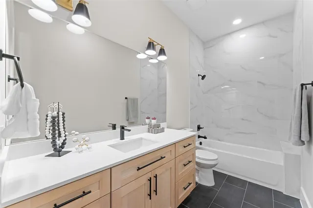 a bathroom with a double vanity sink a toilet a bathtub and shower