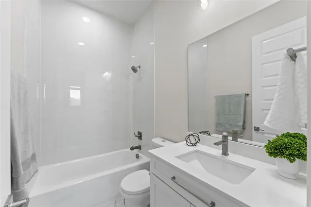 a bathroom with a bathtub shower sink vanity mirror and toilet